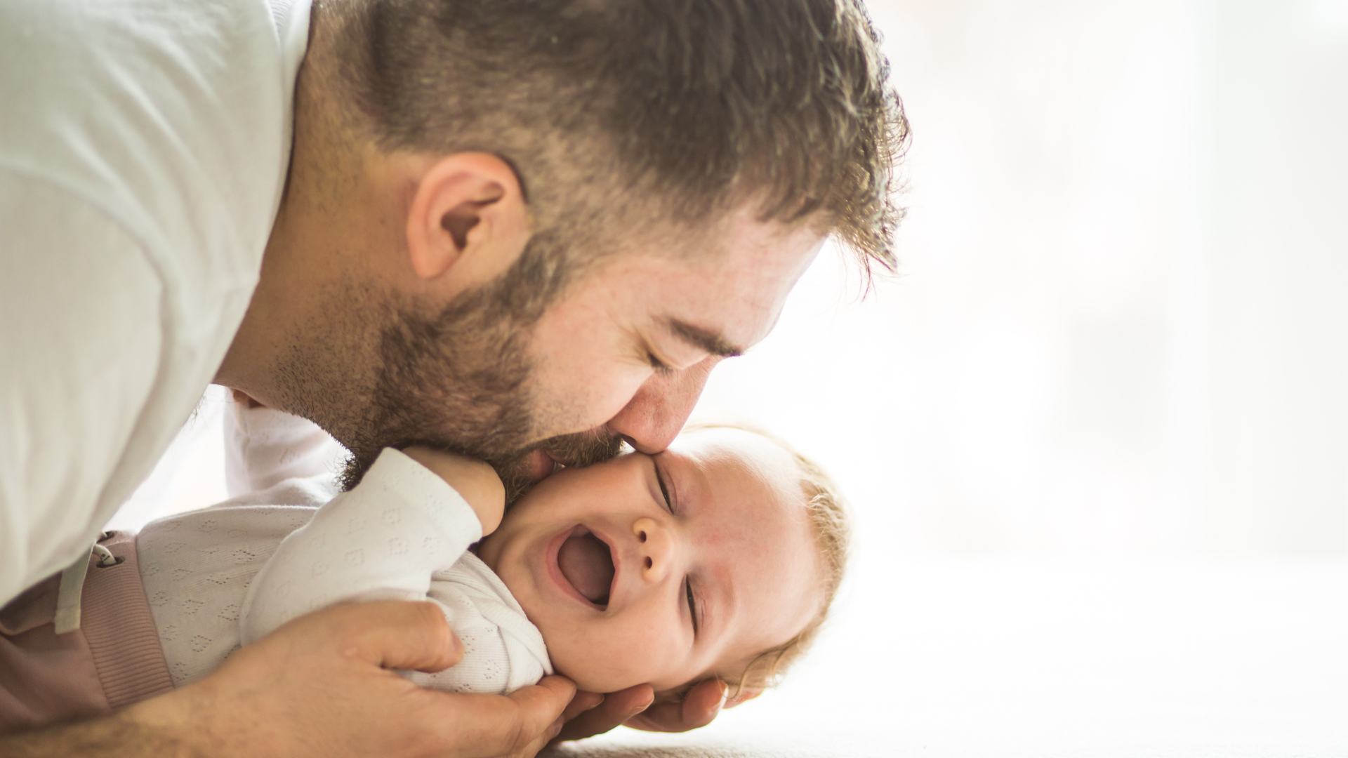Dad kissing his giggling baby